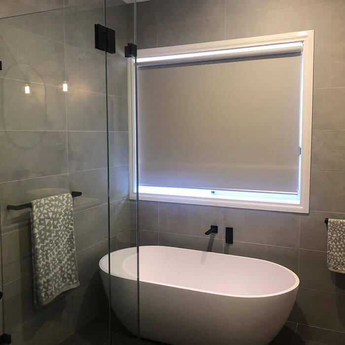 Grey-tiled bathroom with a frameless glass shower and freestanding bathtub