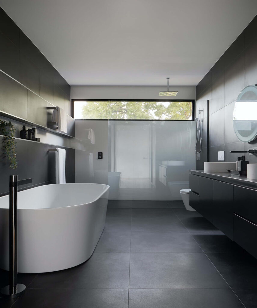 Dark-toned bathroom with pendant lighting, a freestanding bathtub, and floating vanity